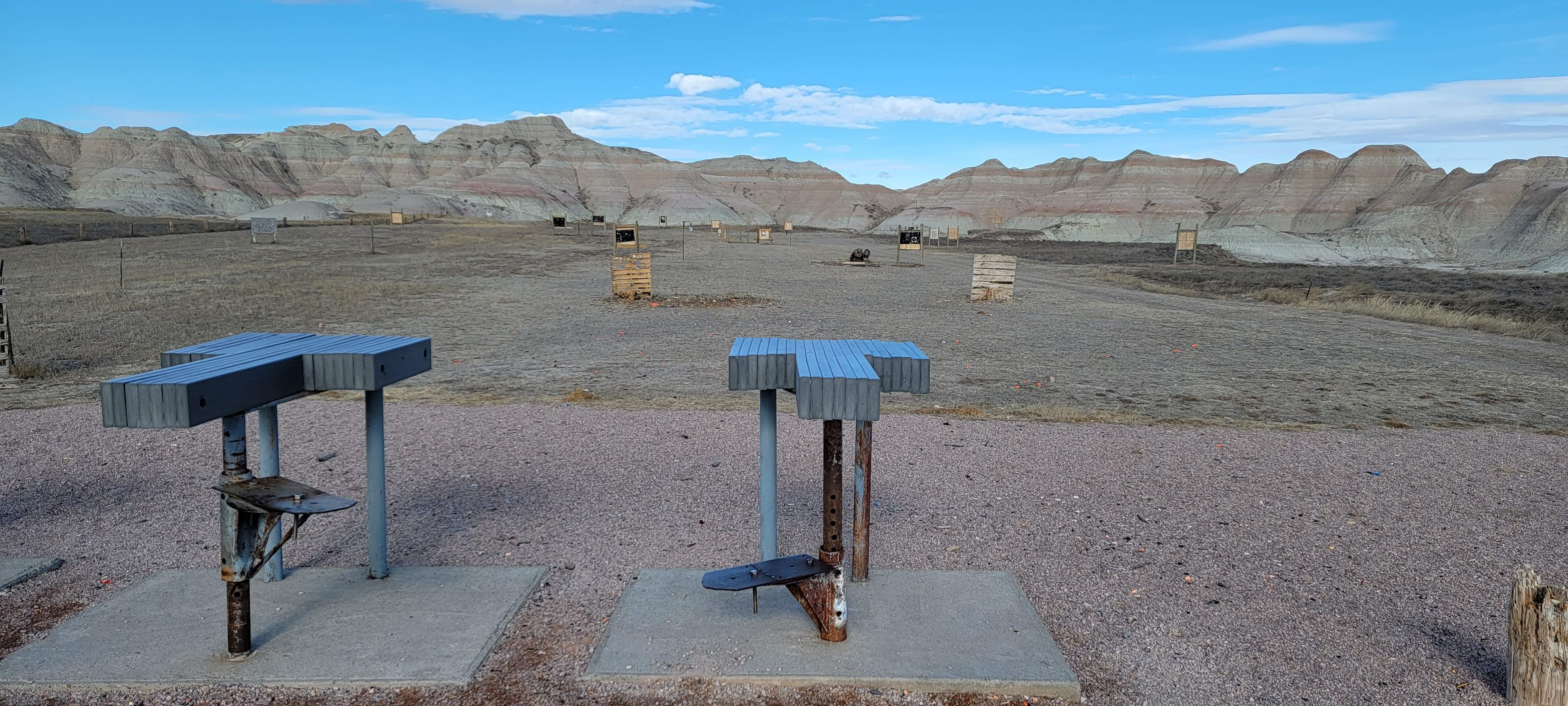 A pair of benches situated in the vast expanse of a desert landscape under a clear blue sky.