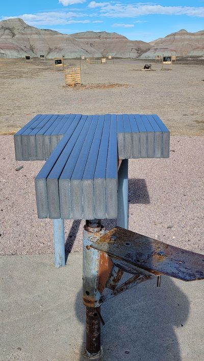 A solitary bench in the desert, adorned with a metal cross, symbolizing reflection and solitude in a vast landscape.