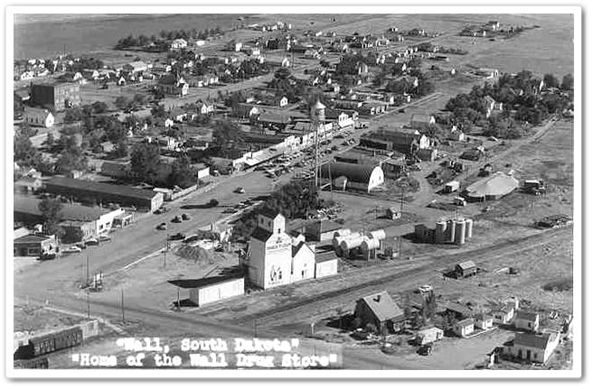 A vintage black and white photograph depicting a quaint town featuring a prominent church in the background.