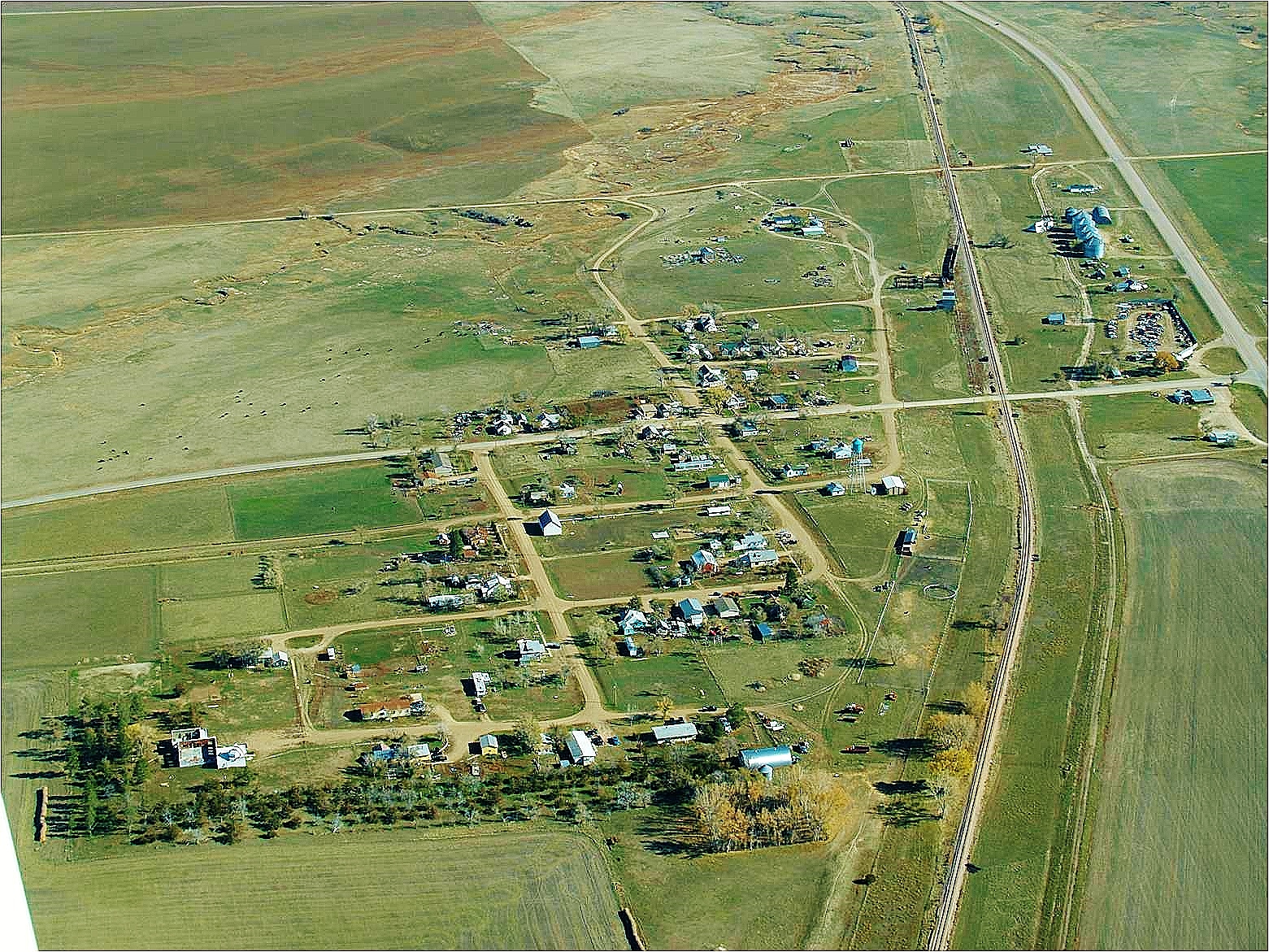 Aerial view of a quaint small town featuring a winding train track amidst residential buildings and green spaces.