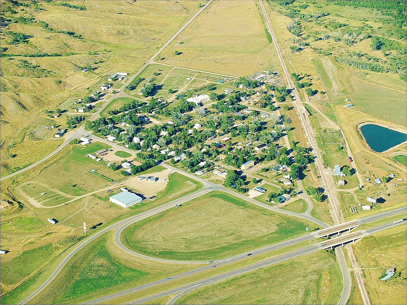Aerial view of a small town featuring a highway and intersecting road, showcasing the layout and surrounding landscape.