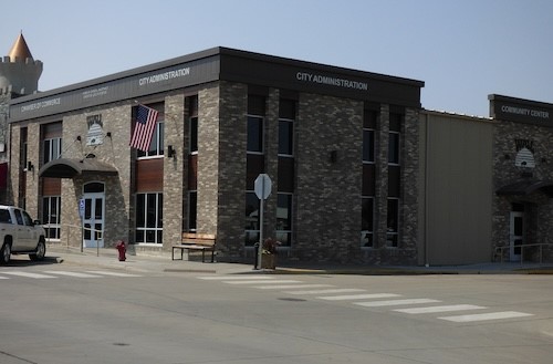 A stone facade building stands prominently beside a white truck parked in front, showcasing a blend of architecture and transport.