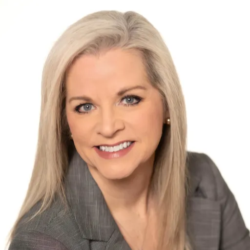 A professional woman with long white hair, dressed in a tailored business suit, exuding confidence and elegance.