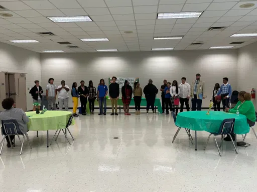 A group of individuals gathered around tables in a spacious room, engaged in conversation and collaboration.