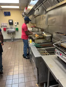 A man skillfully prepares food in a bustling commercial kitchen, surrounded by professional equipment and ingredients.