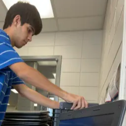 A young boy focused on his laptop, engaged in work or study, with a determined expression on his face.
