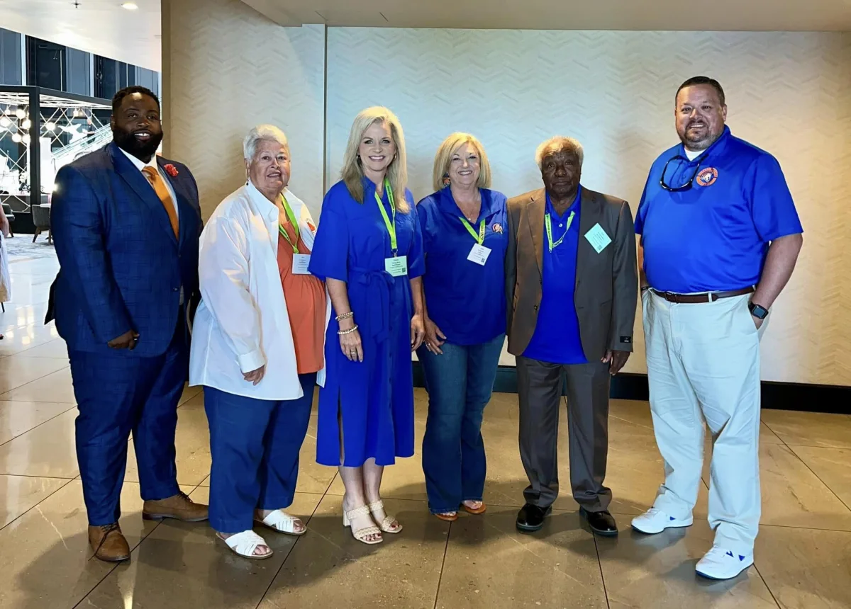 A group of individuals wearing blue shirts and ties stands together, showcasing a unified and professional appearance.