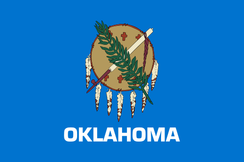 The flag of Oklahoma, featuring a traditional Osage Nation buffalo-skin shield adorned with seven eagle feathers. A peace pipe (calumet) and an olive branch cross over the shield, symbolizing unity between Native American and European-American cultures. The background is a sky blue color, and the word "OKLAHOMA" is written in white capital letters beneath the emblem.