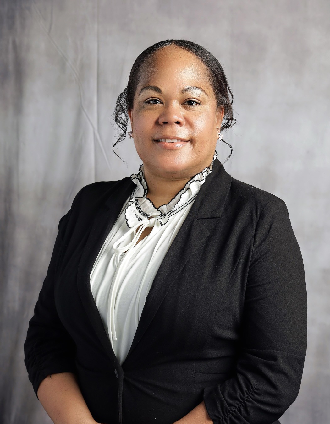 Natasha Myrick: Professional portrait of a smiling woman wearing a black blazer over a white blouse.