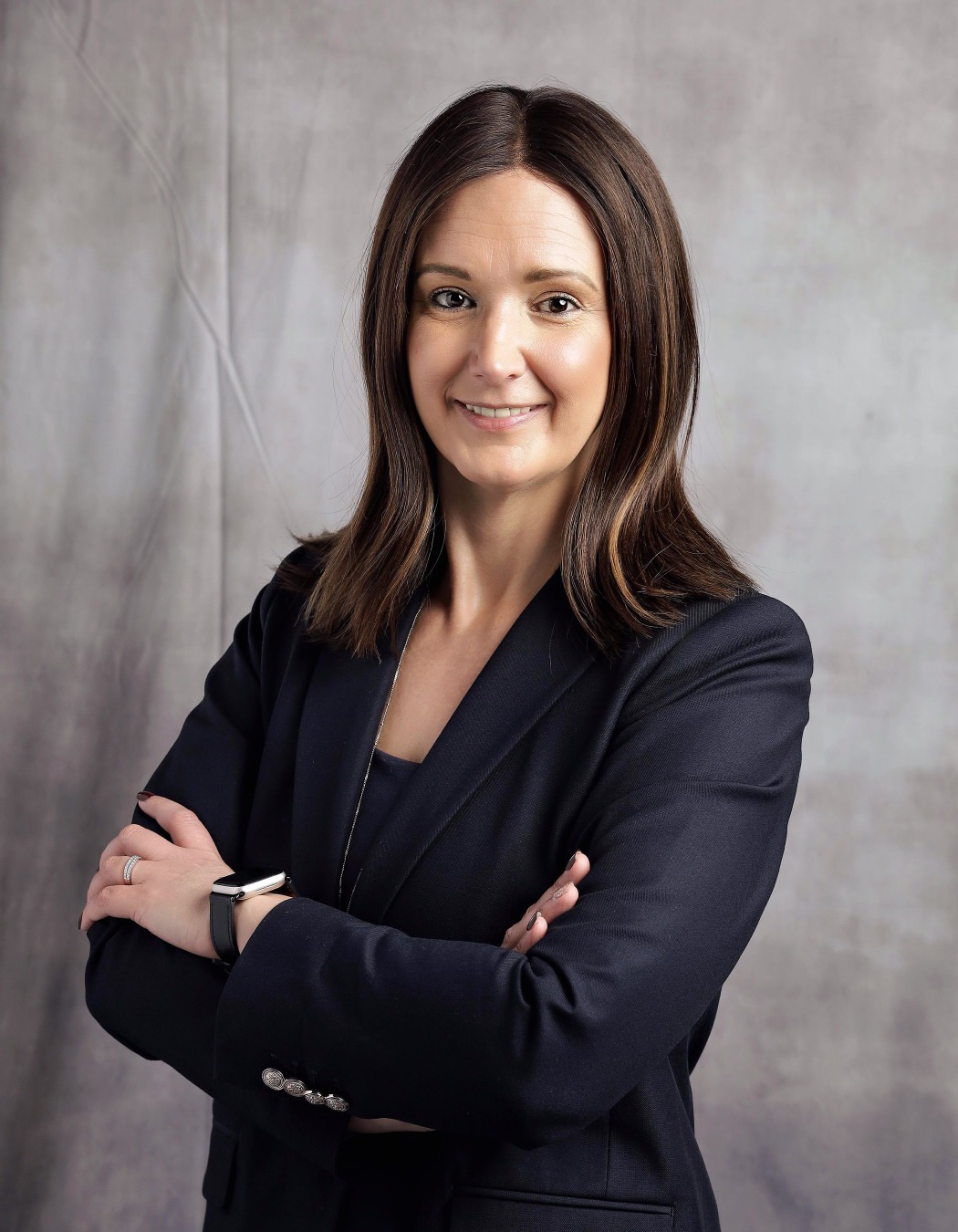 Dr. Airon Grim: Professional portrait of a smiling woman wearing a navy blazer with her arms crossed.