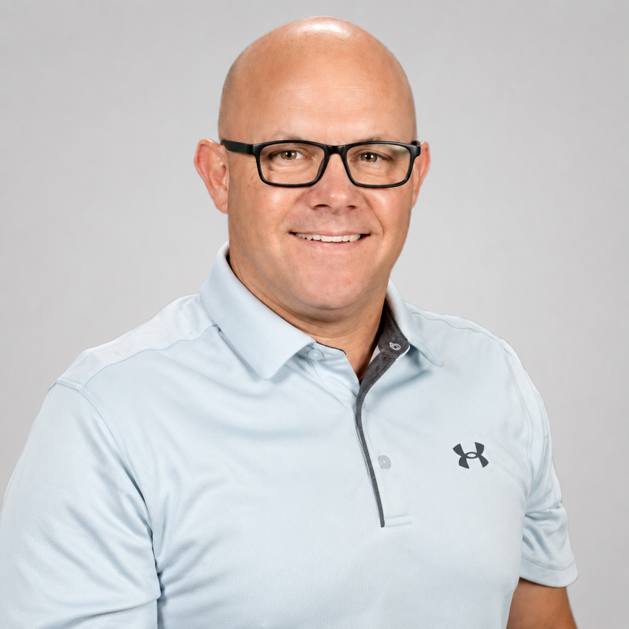 David Trombley: Professional portrait of a smiling man wearing black glasses and a light blue polo shirt.