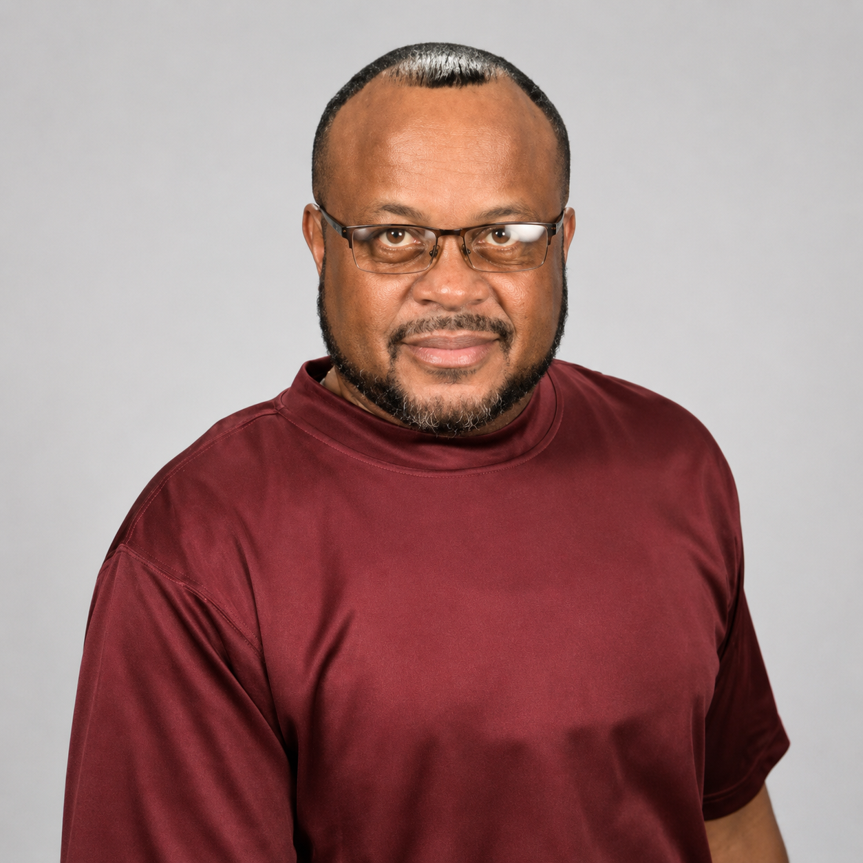 Tim Pierce: Professional portrait of a man wearing glasses and a burgundy shirt.