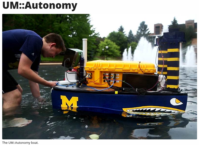 A person is adjusting a small autonomous boat in a fountain, which features a blue and yellow design with a logo on the side.