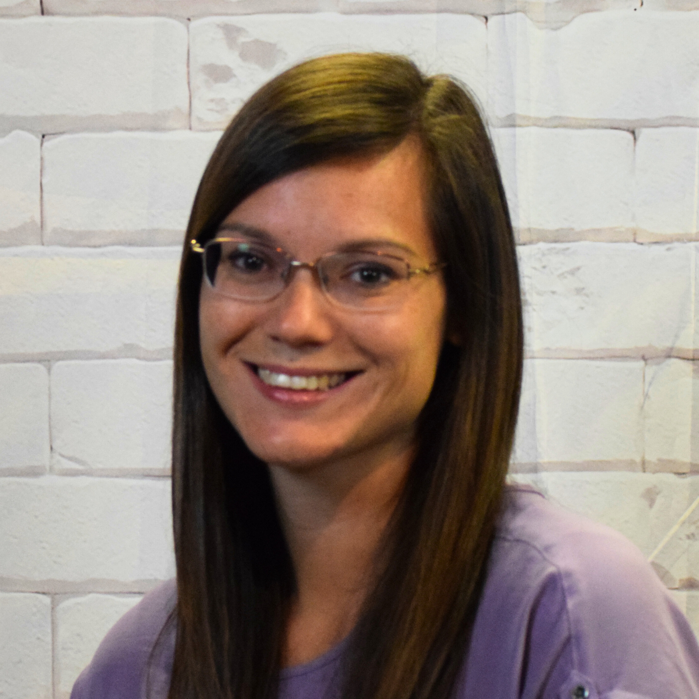 A woman with glasses wearing a plaid shirt, smiling and looking confidently at the camera.