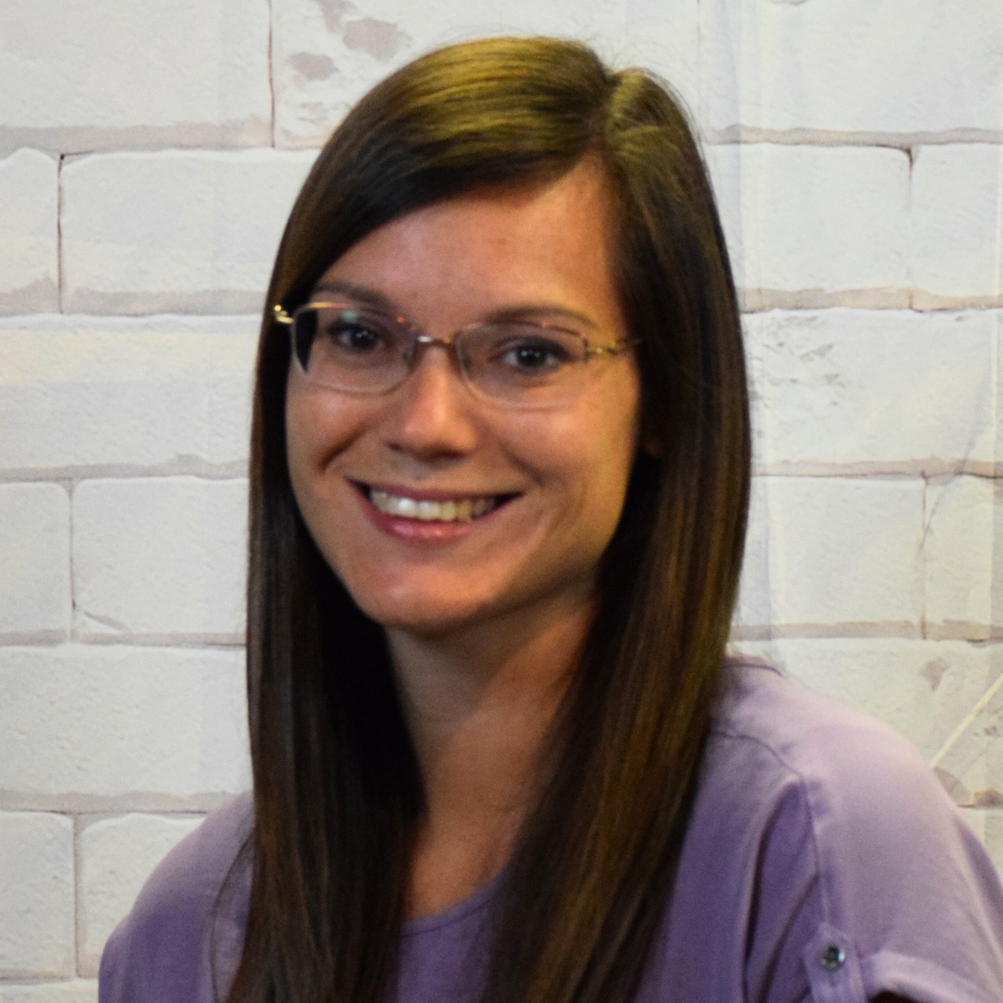  A woman with glasses wearing a plaid shirt, smiling and looking confidently at the camera.