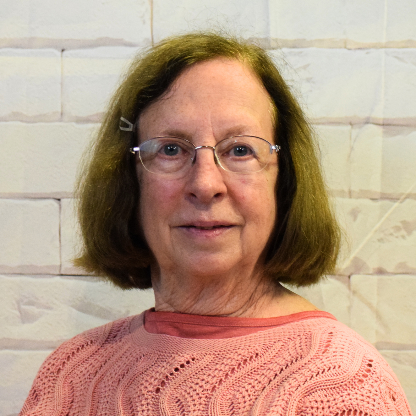 A woman wearing glasses and a black shirt smiles warmly, exuding confidence and approachability.
