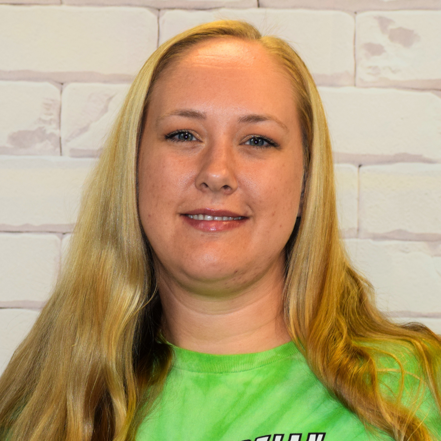 A woman wearing a black hoodie stands confidently in front of a textured brick wall.