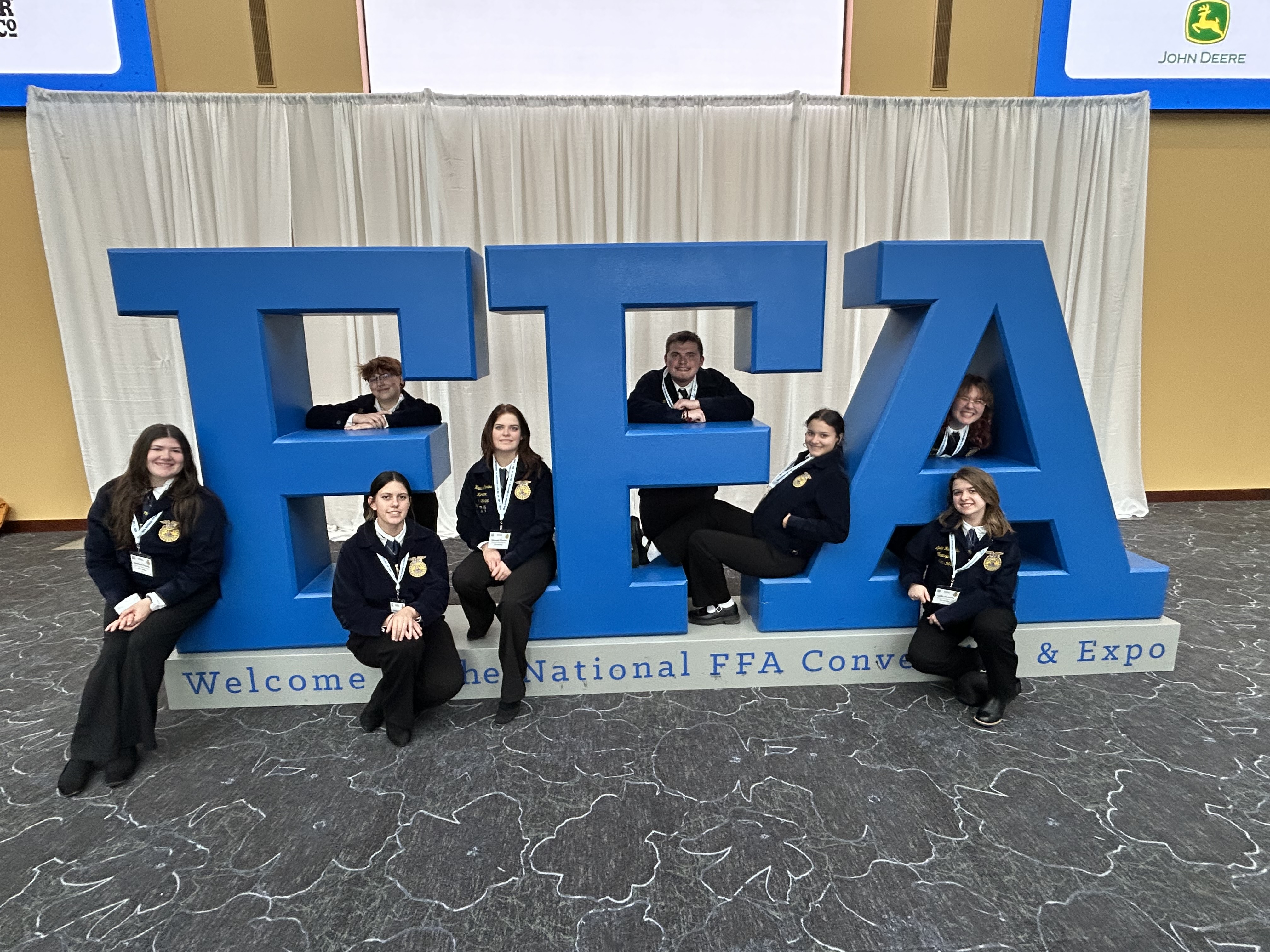 FFA students sitting on an FFA sign.