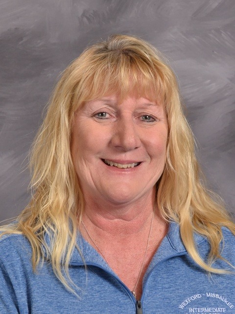 A woman wearing a striped top smiles warmly at the camera, exuding joy and confidence.