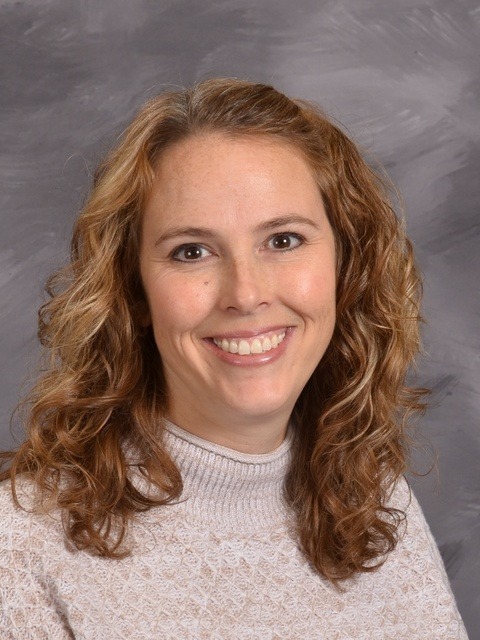 A cheerful woman in a bright yellow sweater beams with a smile, exuding happiness and warmth.