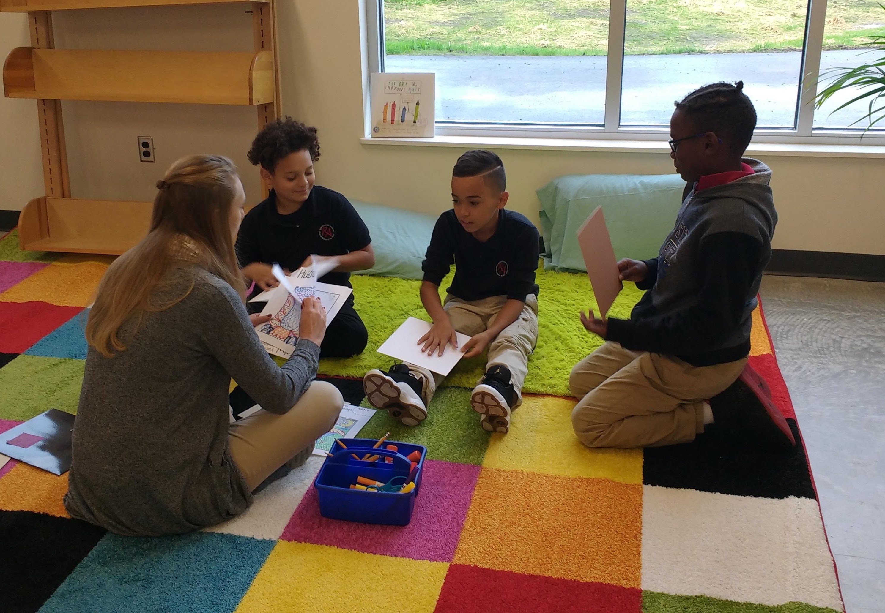 students sit in groups on the floor, crafting