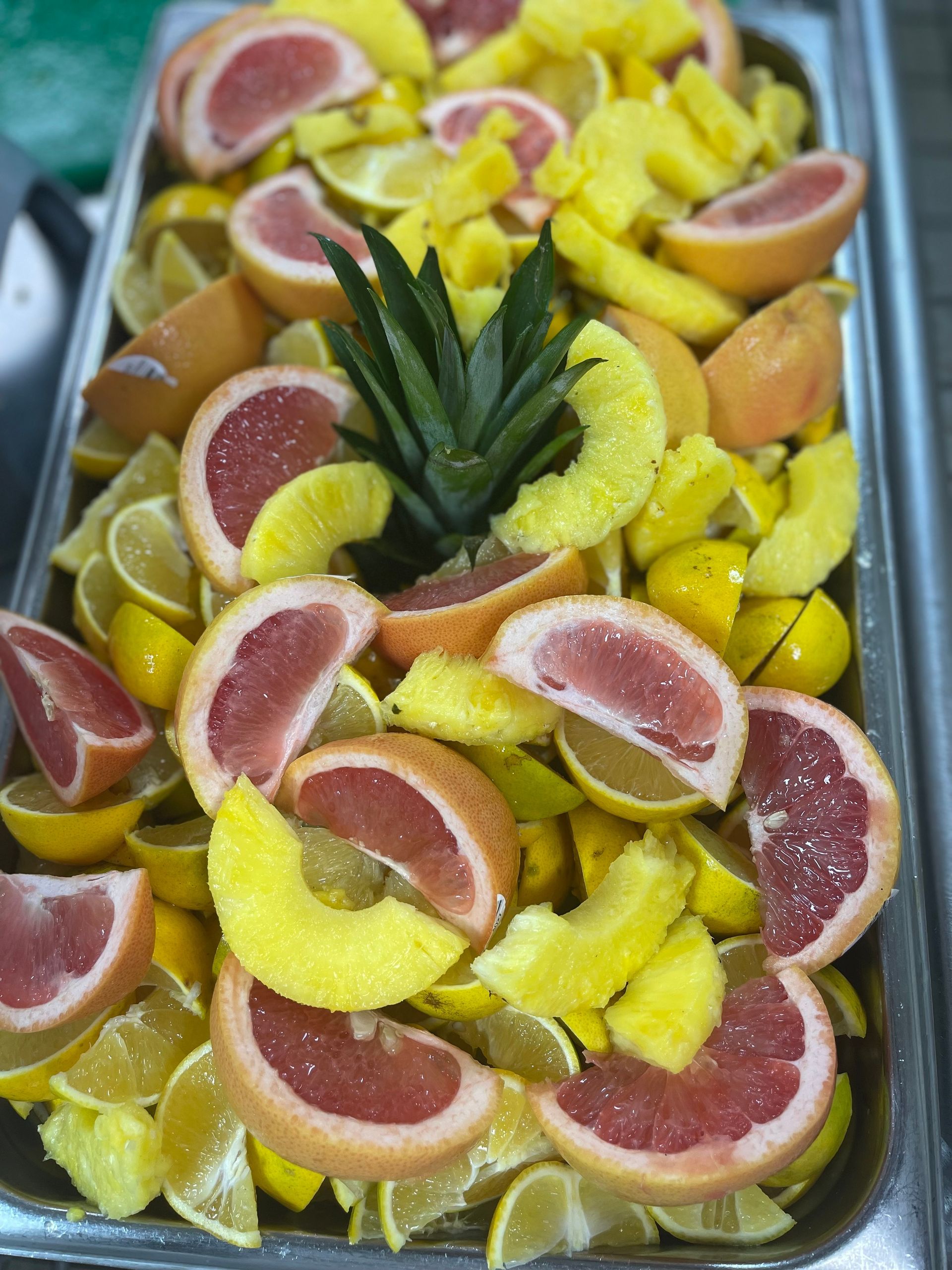A colorful tray displaying an assortment of freshly sliced fruits, including melons, berries, and citrus.