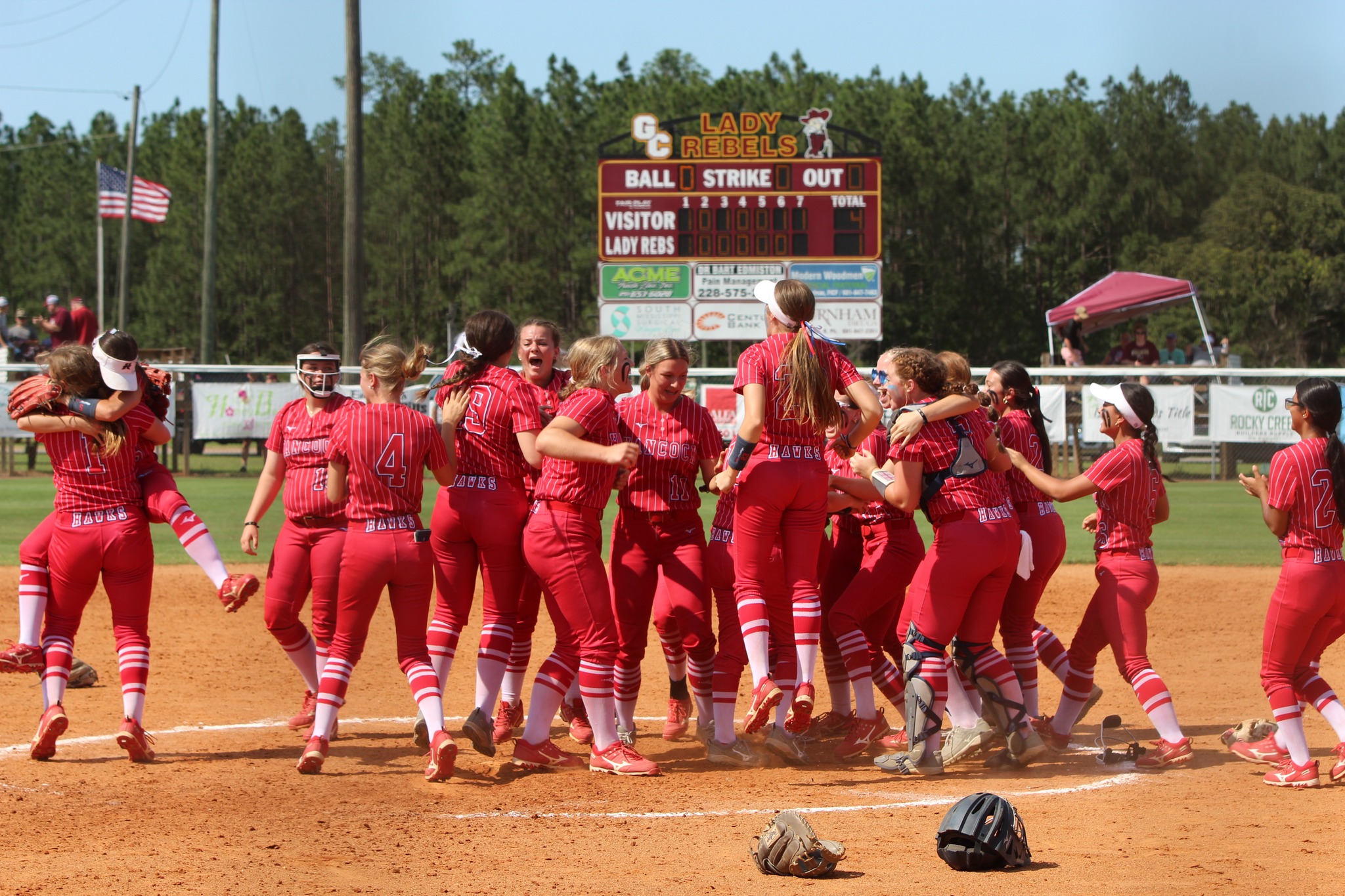 The girls softball team huddling and celebrating on the field. 