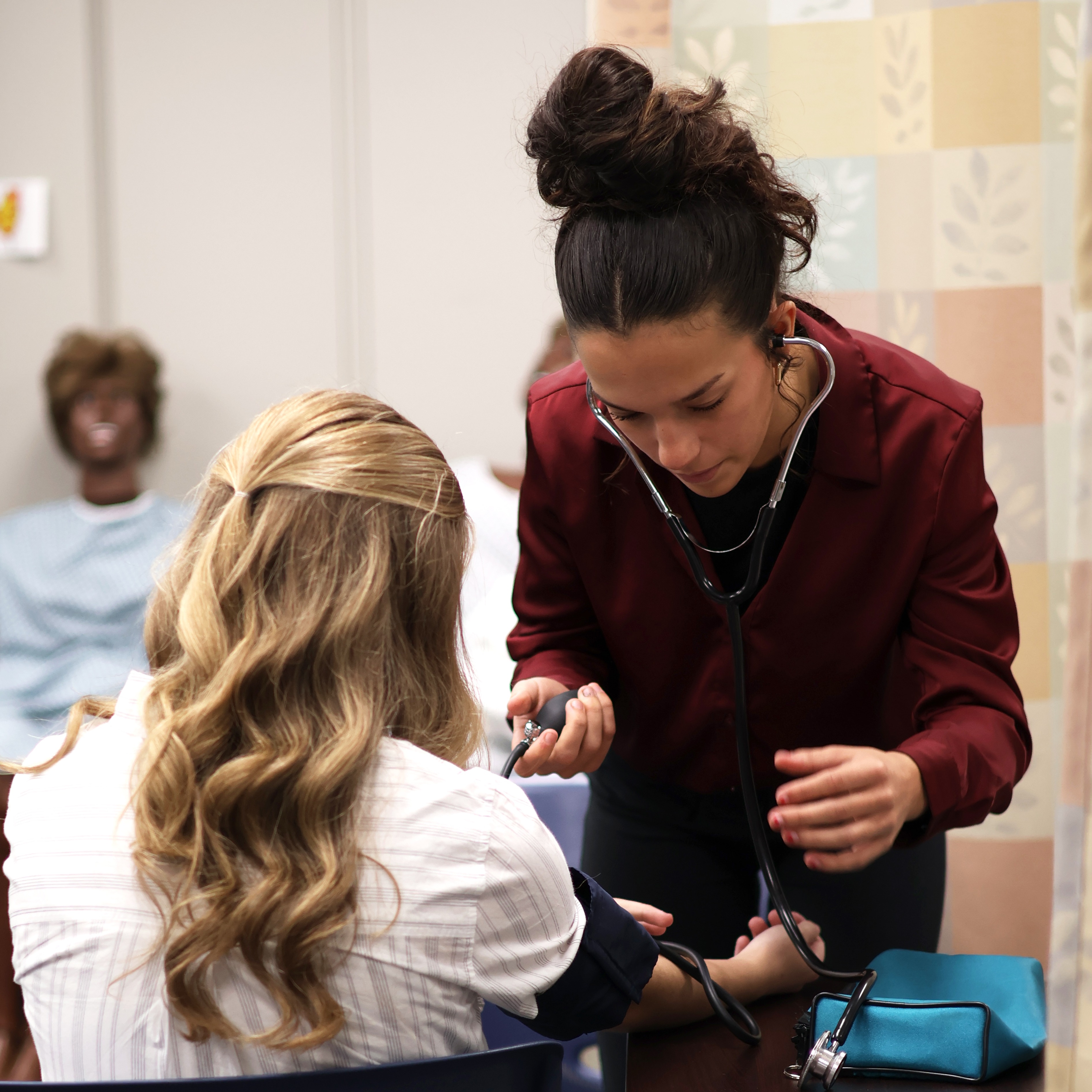 A Health Careers student takes another student's blood pressure with a cuff