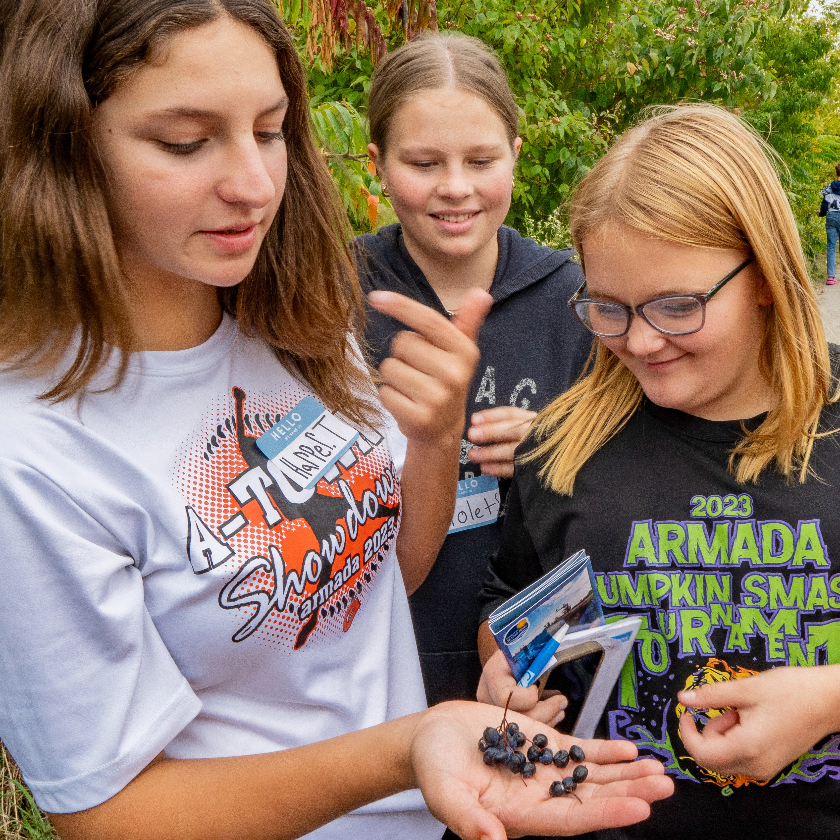 Three students stand togetherwhile one holds a cluster of blu-colored berries in their hand