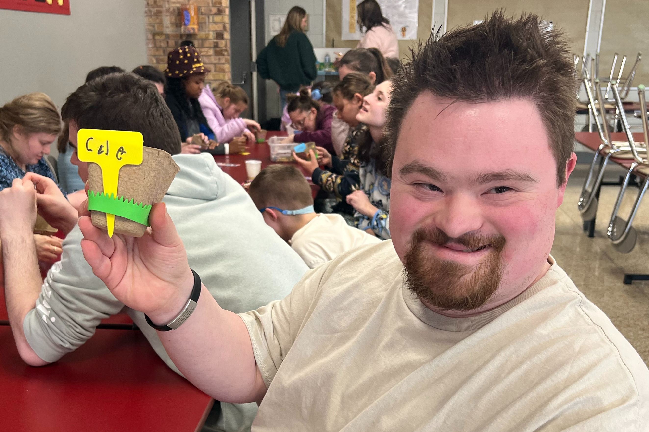 A Woodland student smiles at the camera as he holds the seed cup he decorated during Garden Club