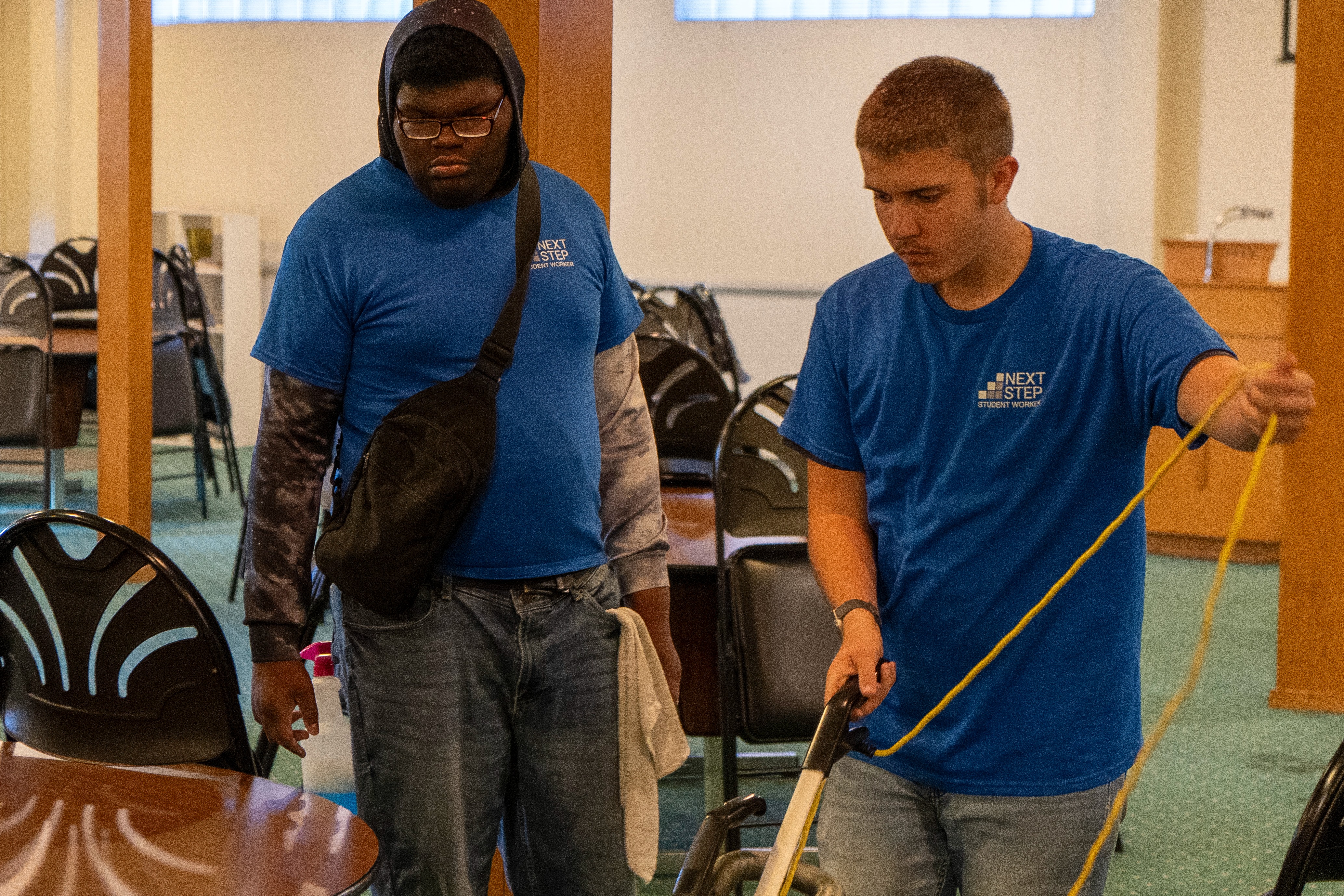 Two Next Step students clean a room and vacuum as part of the program's job skills training