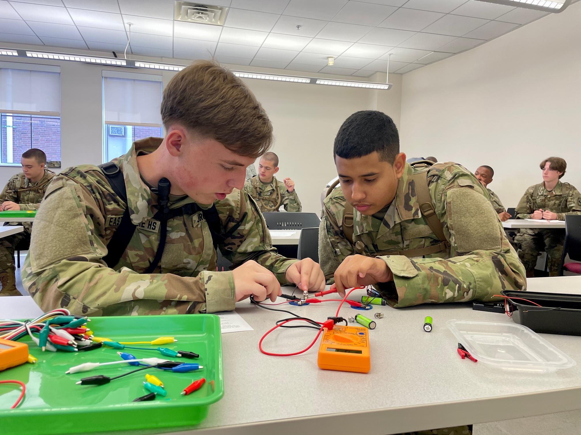 Two uniformed men collaborating on electronic equipment, focused on their task in a professional setting.