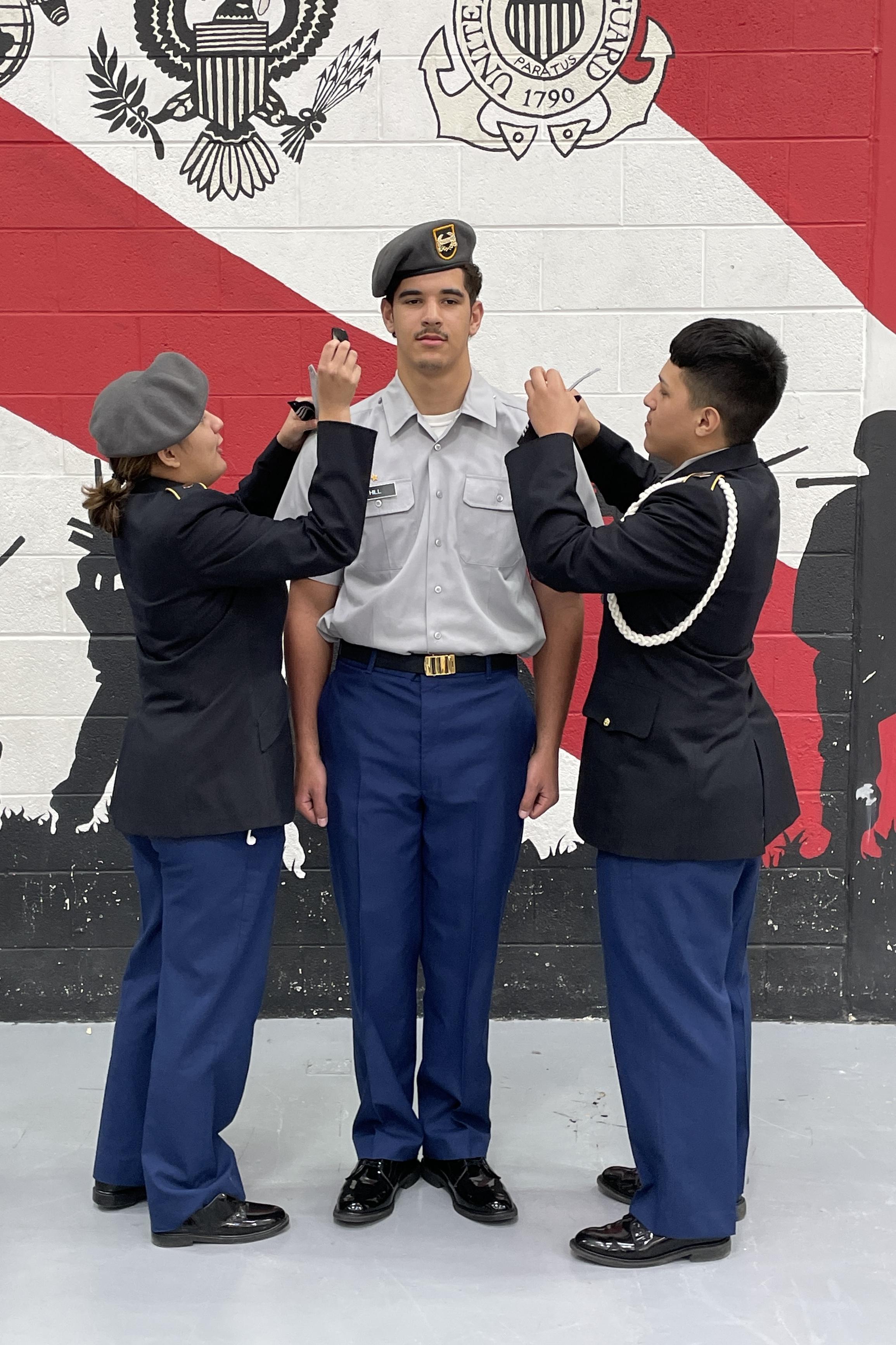 Three uniformed individuals standing together in front of a wall, showcasing teamwork and professionalism.