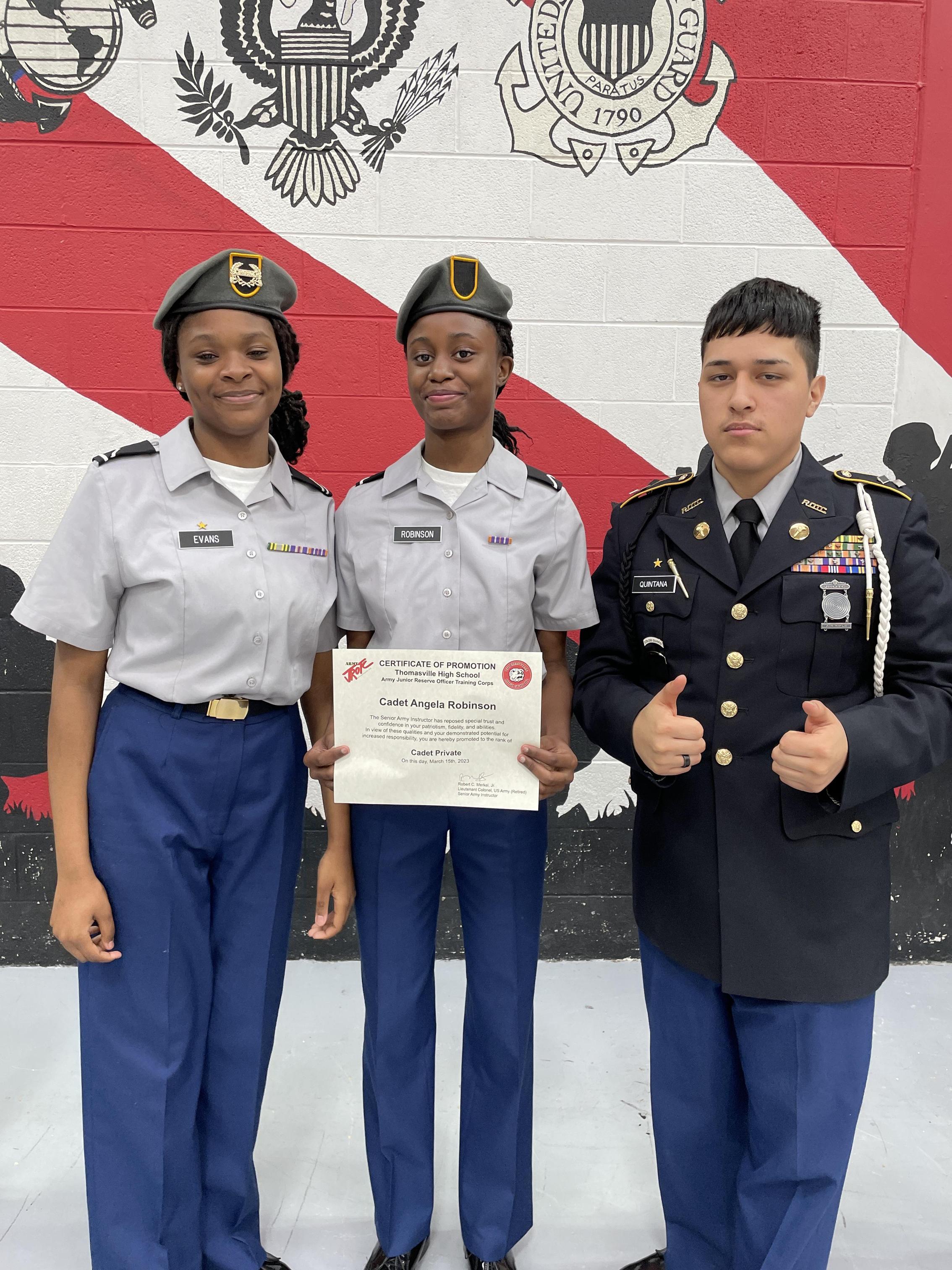 Three military personnel stand together, smiling for a photograph in their uniforms, showcasing camaraderie and pride.