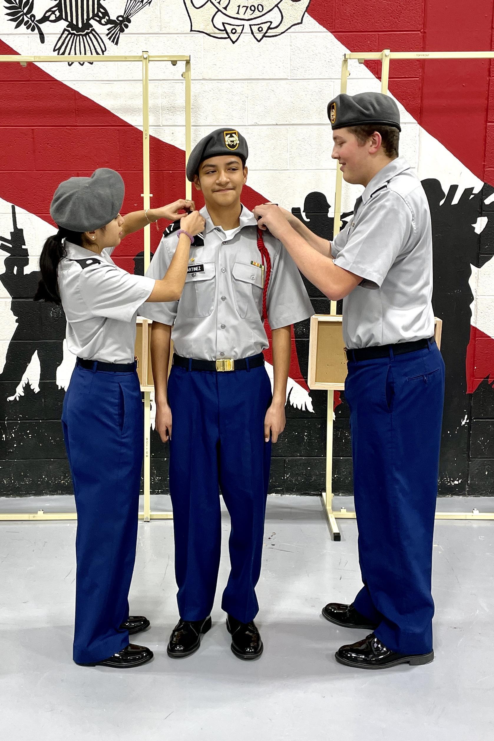 Three uniformed individuals standing together in front of a wall, showcasing teamwork and professionalism.