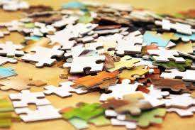 A collection of assorted puzzle pieces scattered on a wooden table surface.