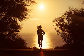 A person runs energetically in the warm glow of the sunset, with vibrant colors illuminating the sky.