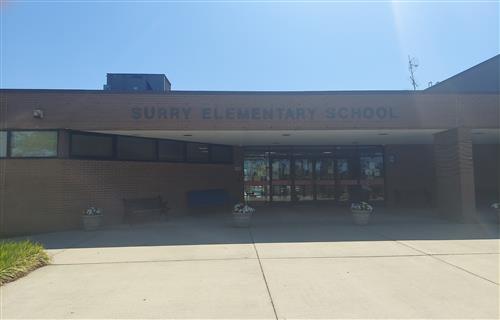 A sunny view of the entrance to an elementary school, featuring large windows and the name 'Durry Elementary School' prominently displayed above the entrance.