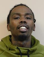 A man with short hair and a green hoodie smiles at the camera, showing his teeth.
