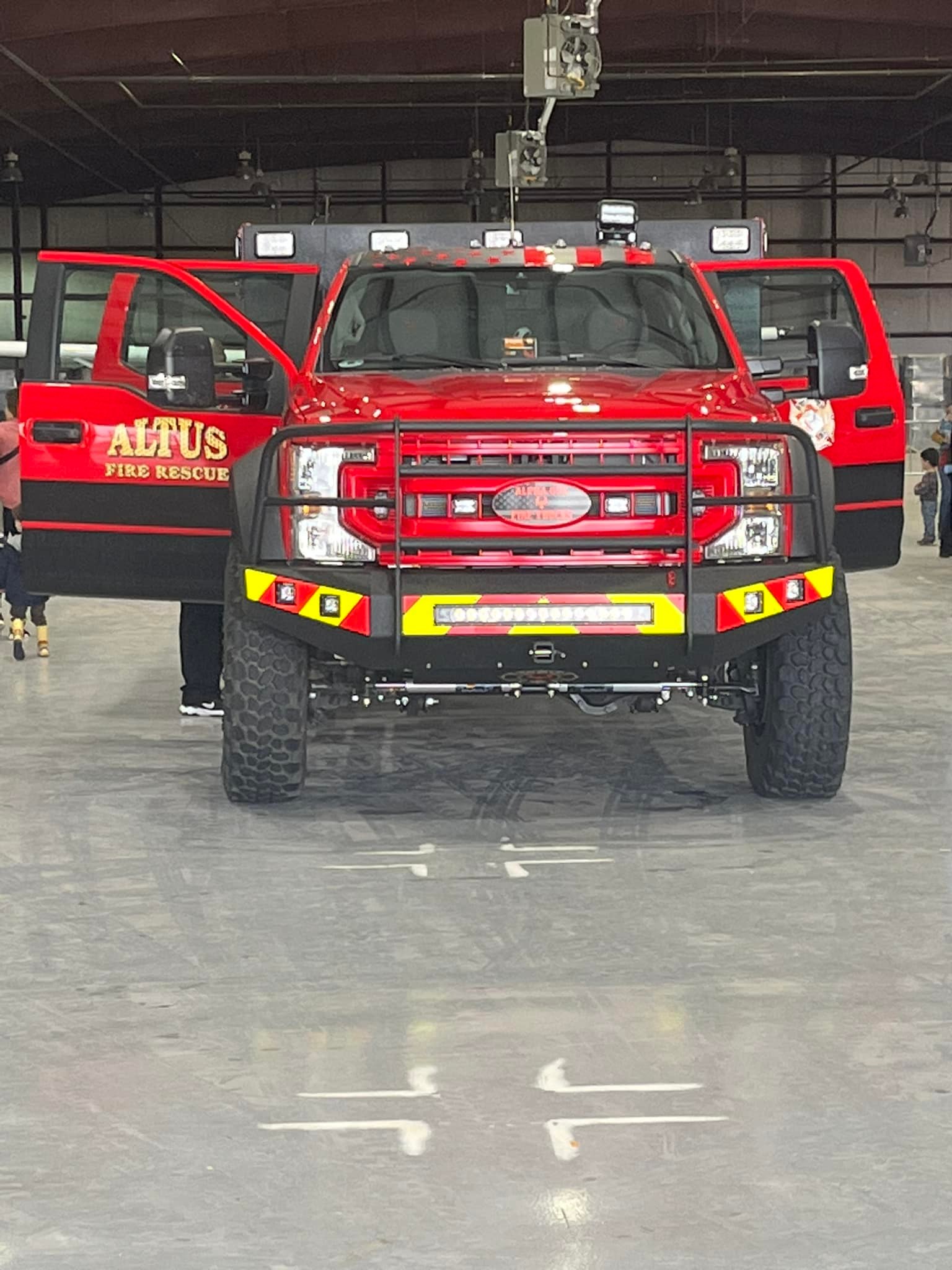 Front view of an Altus Fire Rescue emergency response vehicle inside a large indoor facility, with its doors open and emergency lights mounted on top.