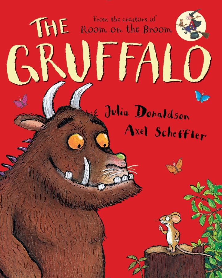 A large, mythical creature with a fierce expression, resembling a monster from a children's storybook, stands in a forest setting.