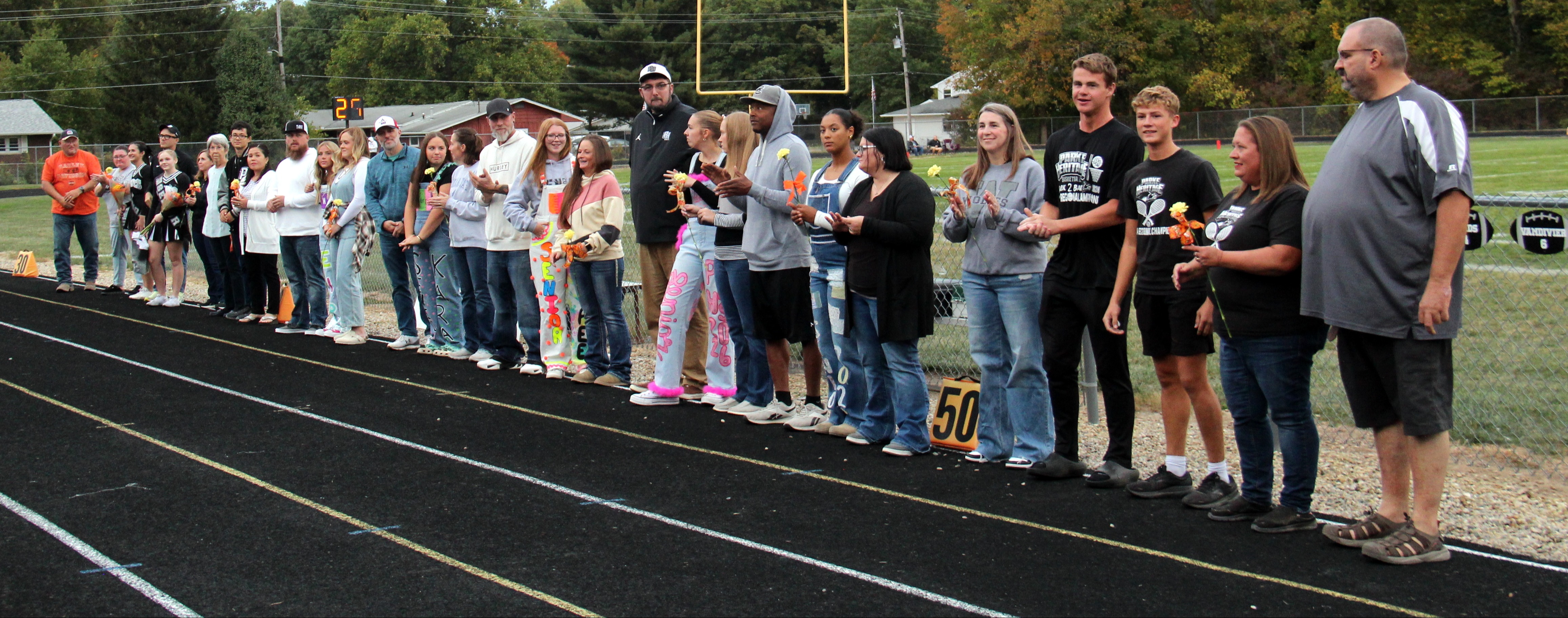 seniors and their parents standing along the track on senior night recognition