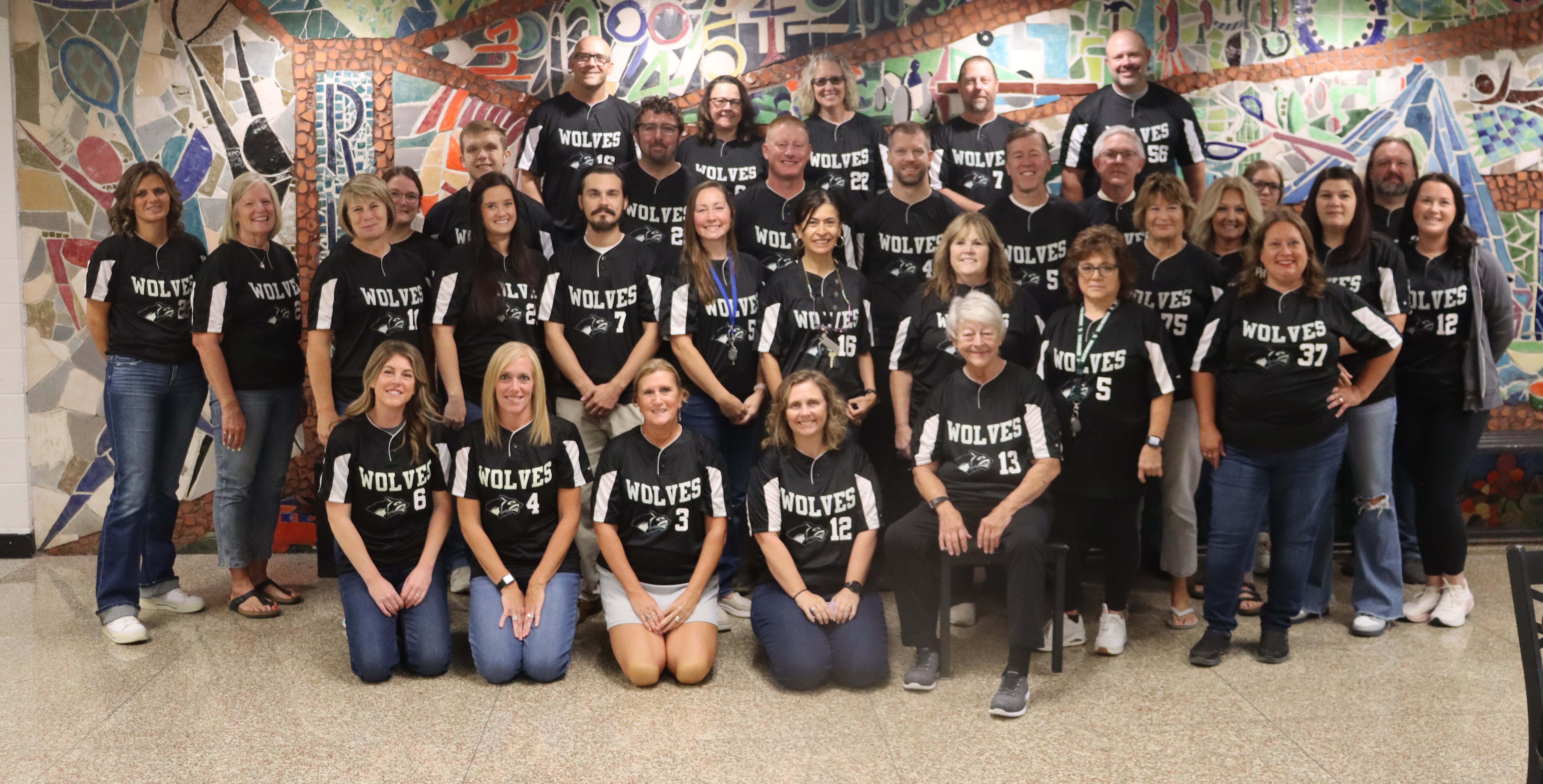 rows of staff members sitting, kneeling or standing
