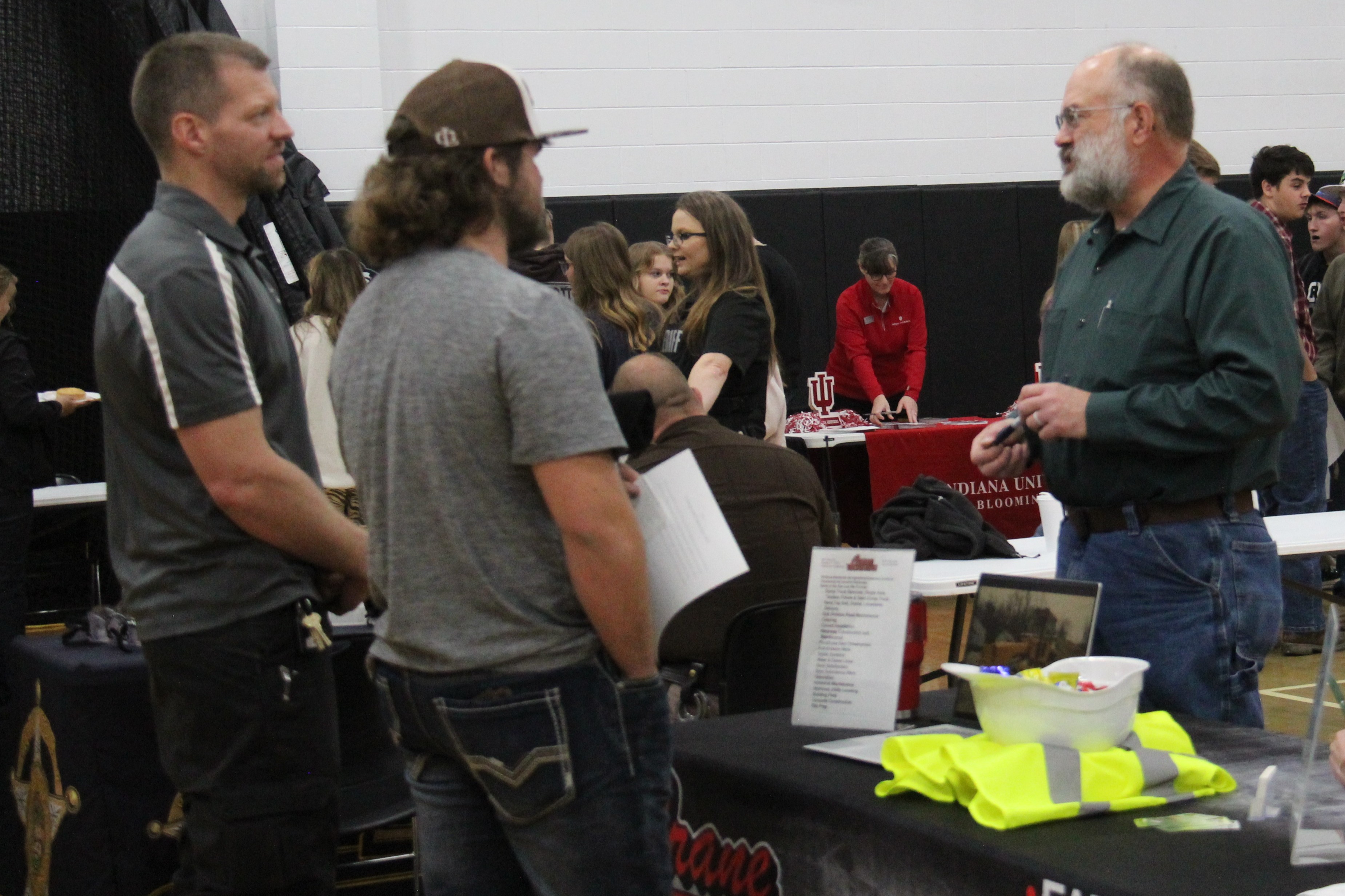 student and a teacher talking to a business representative at the college and career fair