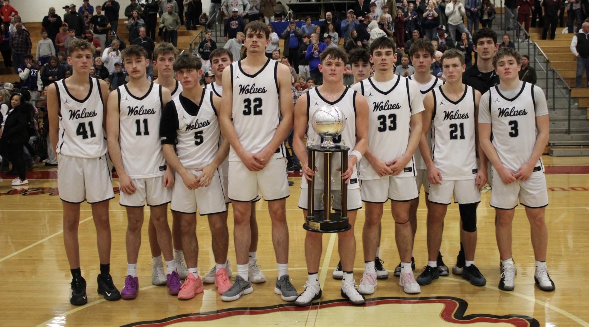 boys basketball players standing in a line with one of the holding a trophy