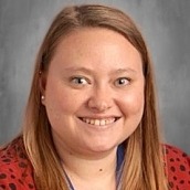 Woman with long blond hair wearing a red leopard-print shirt and a blue lanyard smiles.