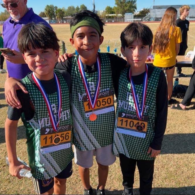 3 students posing with school jerseys on and award medals