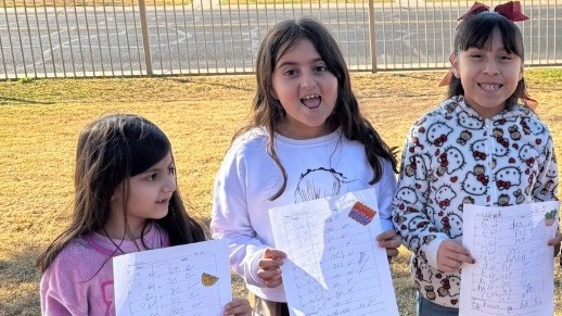 Students holding up homework they did well on