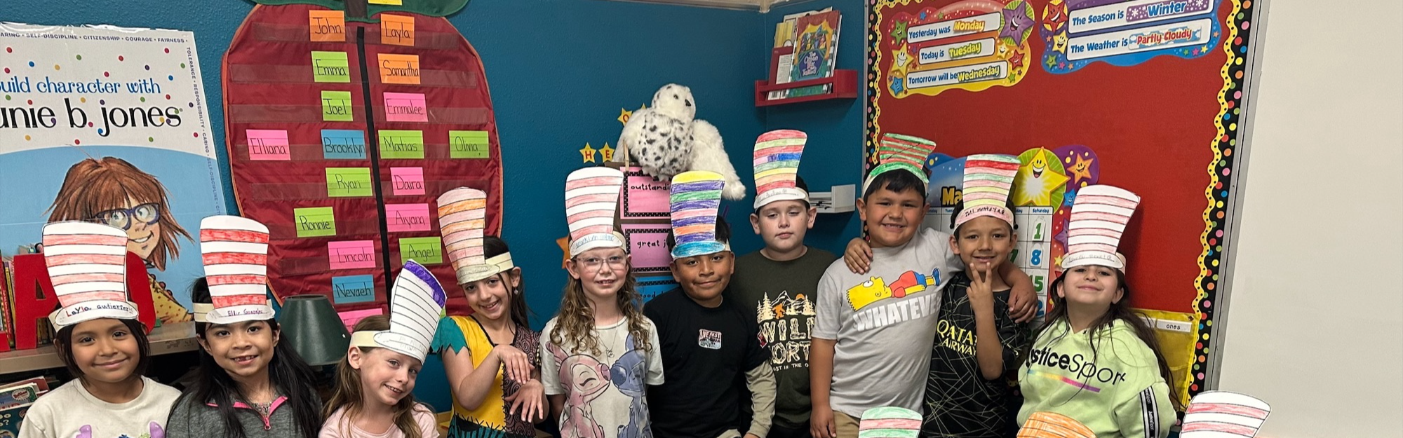 Elementary students posing with Cat in the Hat hats on