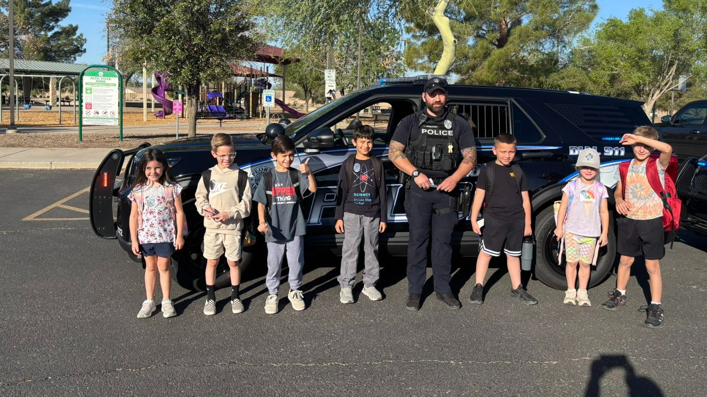 School Liaison Officer with students in front of a police car